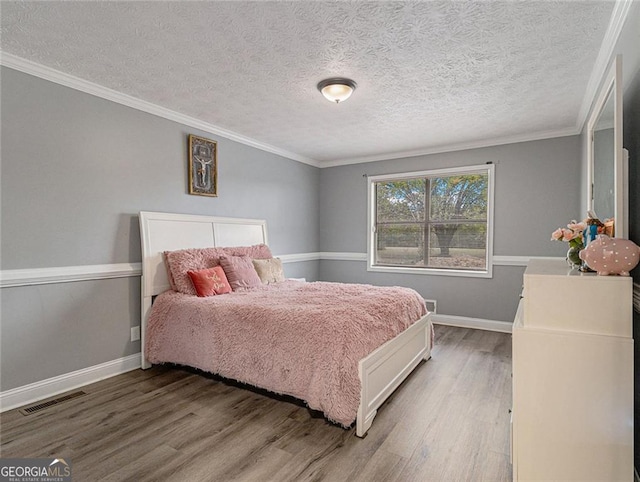 bedroom with hardwood / wood-style flooring, a textured ceiling, and crown molding