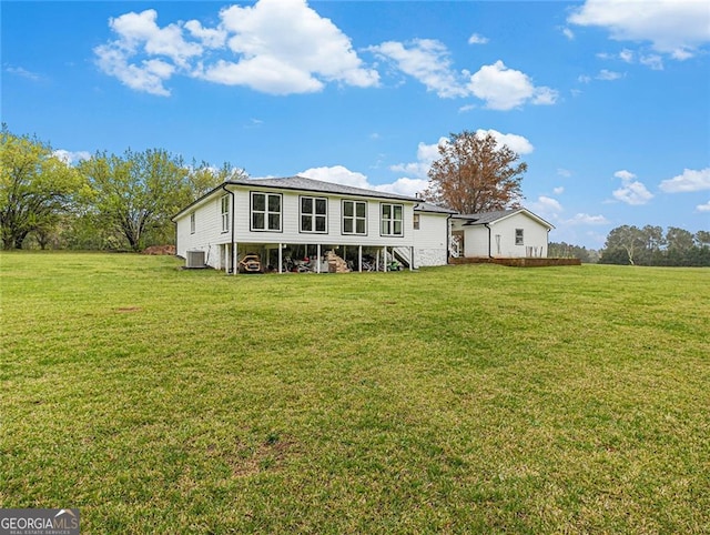 back of property featuring central air condition unit and a yard