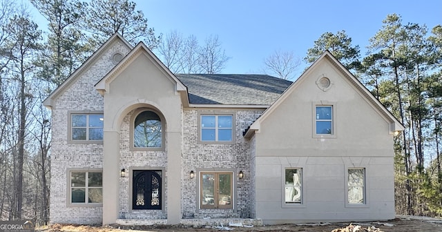 view of front facade featuring french doors, brick siding, and a shingled roof