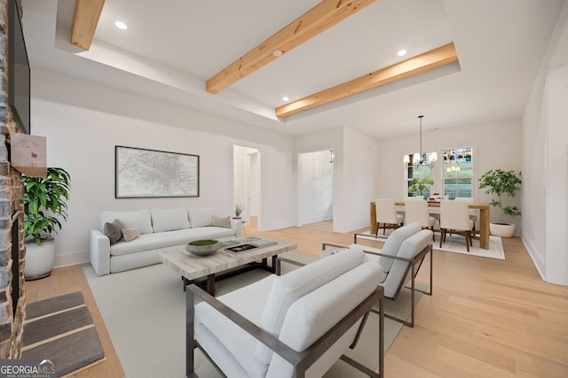 living room featuring light wood-type flooring, a chandelier, and a raised ceiling