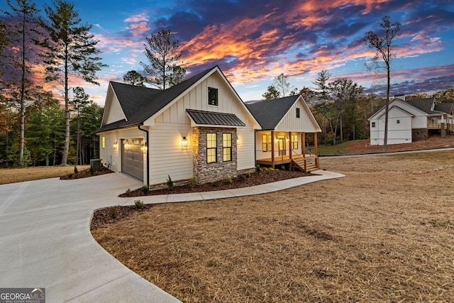 view of front of property featuring central air condition unit, covered porch, and a garage