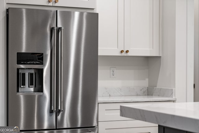 kitchen with white cabinets, stainless steel refrigerator with ice dispenser, and light stone counters