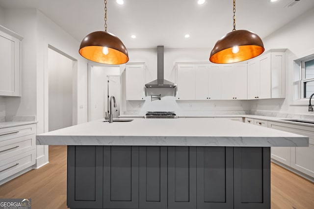 kitchen featuring white cabinetry, wall chimney exhaust hood, and hanging light fixtures