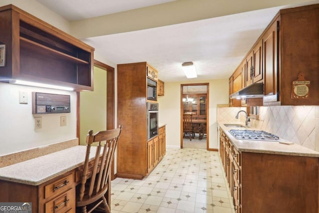 kitchen featuring backsplash, sink, light stone countertops, and stainless steel appliances