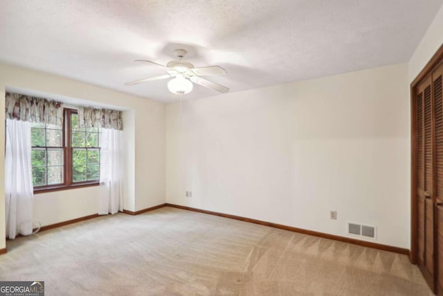 carpeted spare room featuring a textured ceiling and ceiling fan