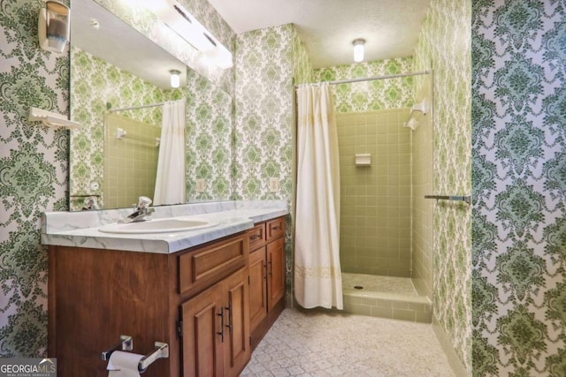 bathroom with walk in shower, vanity, and a textured ceiling