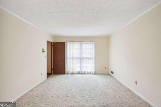 spare room featuring a textured ceiling, light colored carpet, and crown molding