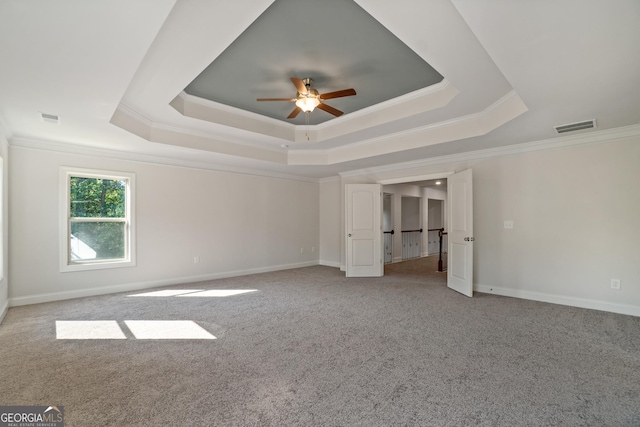 carpeted empty room with ceiling fan, a raised ceiling, and ornamental molding