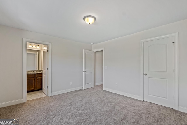 unfurnished bedroom with ensuite bathroom and light colored carpet