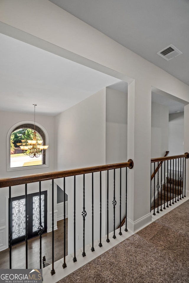 corridor featuring carpet floors and an inviting chandelier