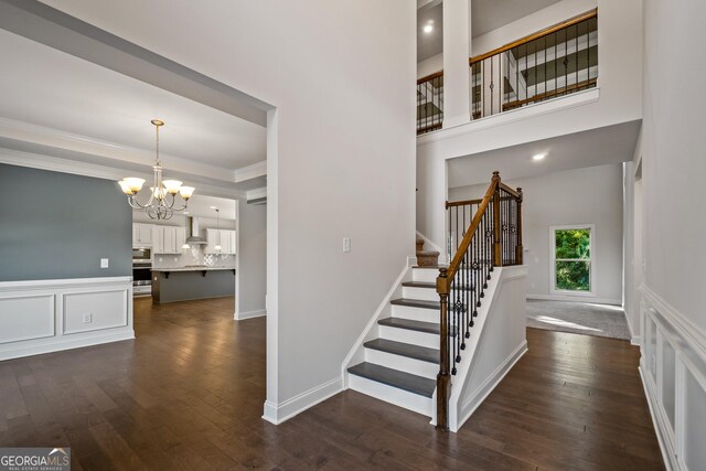 staircase featuring hardwood / wood-style floors, a notable chandelier, and ornamental molding