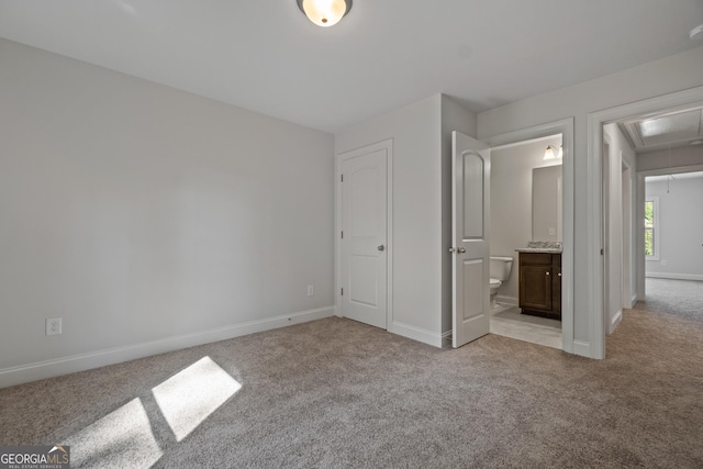 unfurnished bedroom featuring light colored carpet and ensuite bathroom