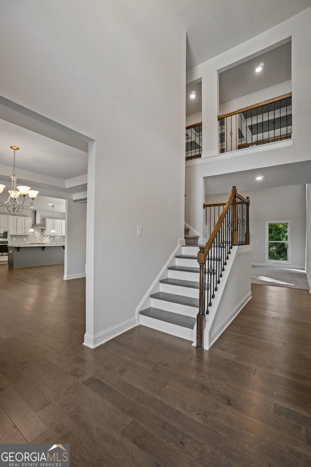 staircase featuring a raised ceiling, a chandelier, and hardwood / wood-style flooring