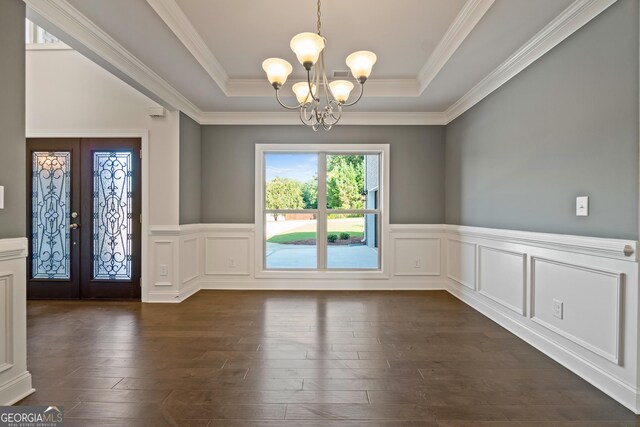 unfurnished dining area featuring a chandelier, crown molding, a tray ceiling, and french doors