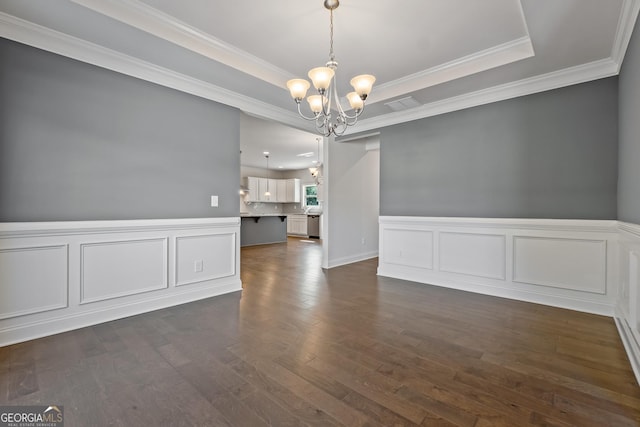 spare room featuring dark hardwood / wood-style floors, crown molding, and a chandelier