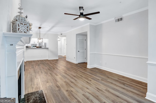 unfurnished living room featuring ceiling fan, wood-type flooring, and crown molding