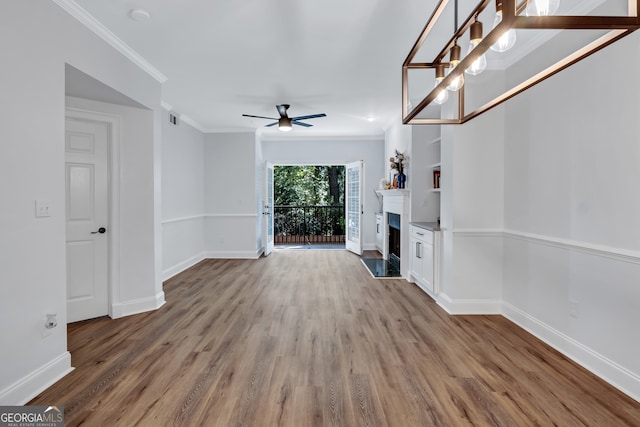 unfurnished living room featuring hardwood / wood-style flooring, ceiling fan, and crown molding