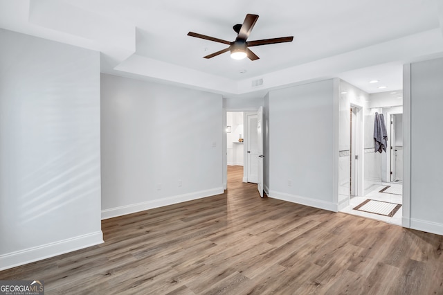 unfurnished bedroom with ensuite bathroom, hardwood / wood-style floors, ceiling fan, and a closet