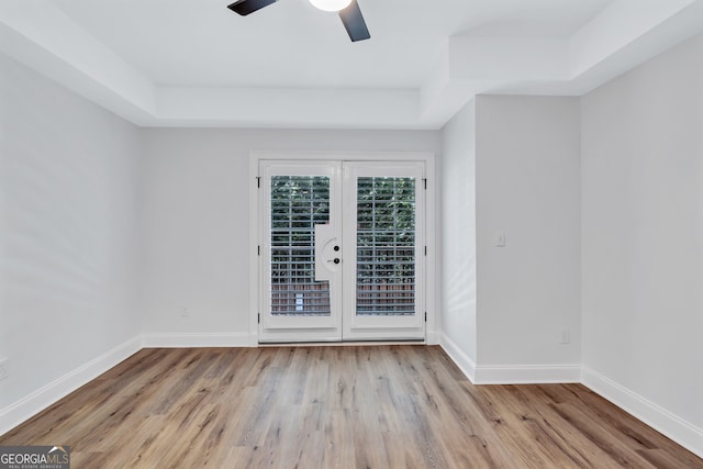 spare room featuring light hardwood / wood-style floors, ceiling fan, and a raised ceiling