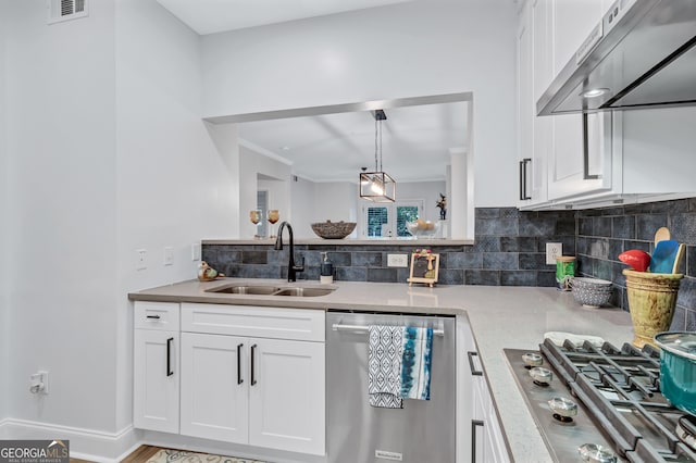 kitchen with sink, backsplash, white cabinetry, appliances with stainless steel finishes, and decorative light fixtures