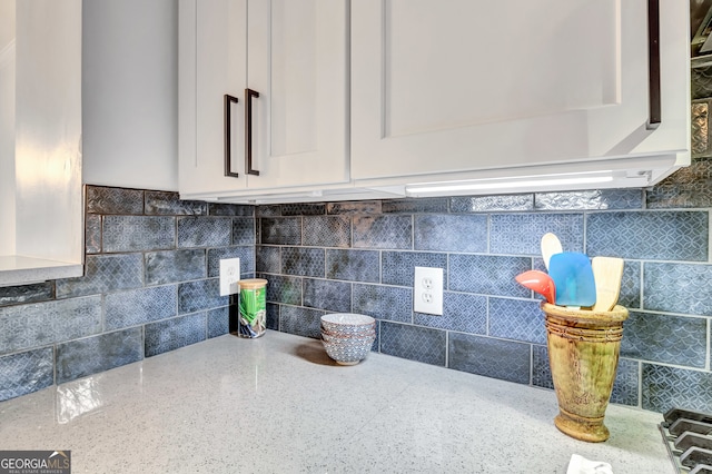 room details featuring white cabinets, tasteful backsplash, and light stone countertops