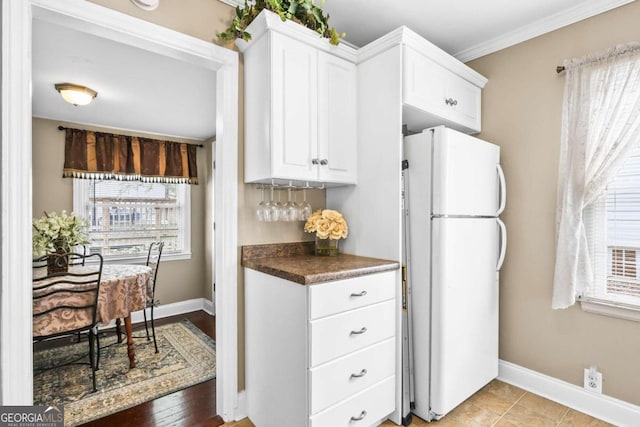 kitchen featuring light wood-type flooring, white refrigerator, a healthy amount of sunlight, and white cabinets