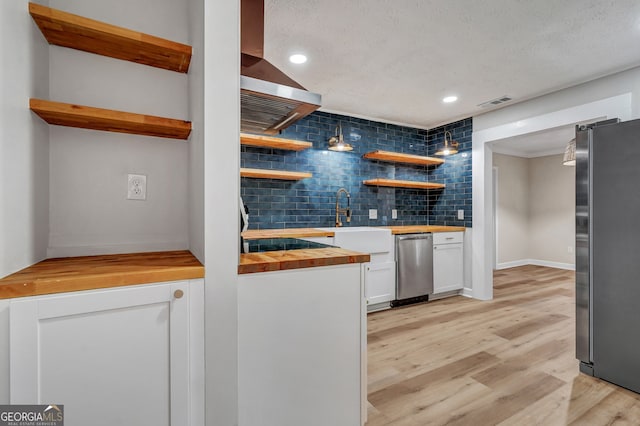 kitchen with white cabinetry, stainless steel appliances, wood counters, tasteful backsplash, and light hardwood / wood-style flooring