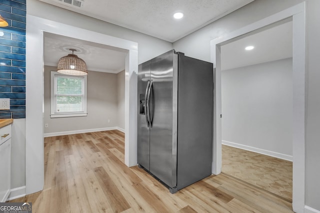 kitchen featuring stainless steel fridge with ice dispenser, white cabinetry, light hardwood / wood-style flooring, and pendant lighting