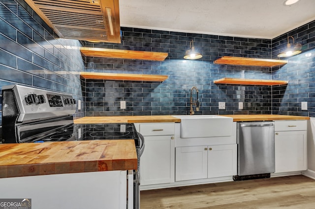 kitchen featuring white cabinetry, sink, wooden counters, appliances with stainless steel finishes, and light wood-type flooring