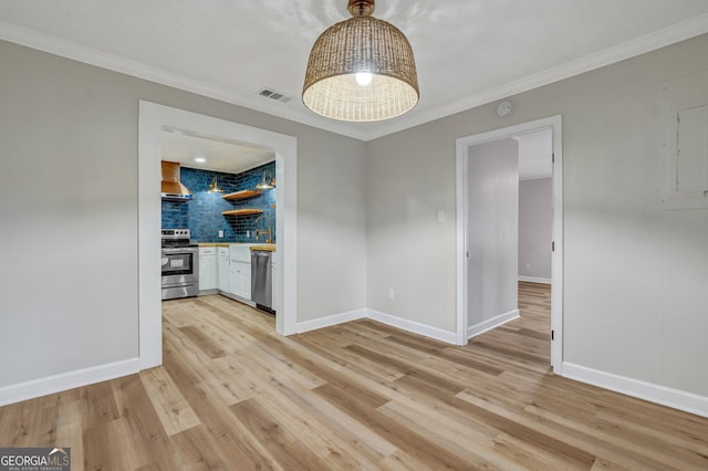 unfurnished dining area featuring ornamental molding, sink, electric panel, and light hardwood / wood-style flooring