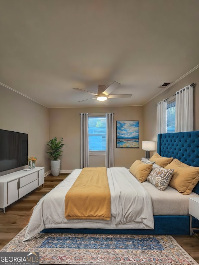 bedroom featuring multiple windows, ceiling fan, dark hardwood / wood-style flooring, and ornamental molding