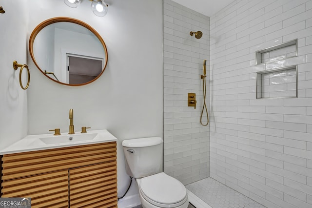 bathroom featuring tiled shower, vanity, and toilet