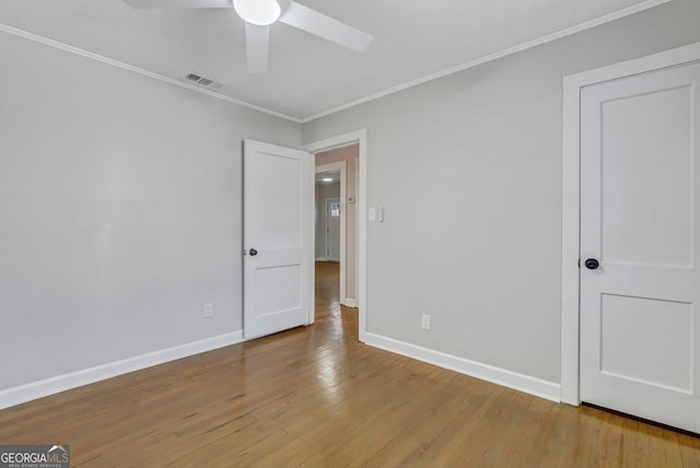 unfurnished room with hardwood / wood-style floors, ceiling fan, and crown molding