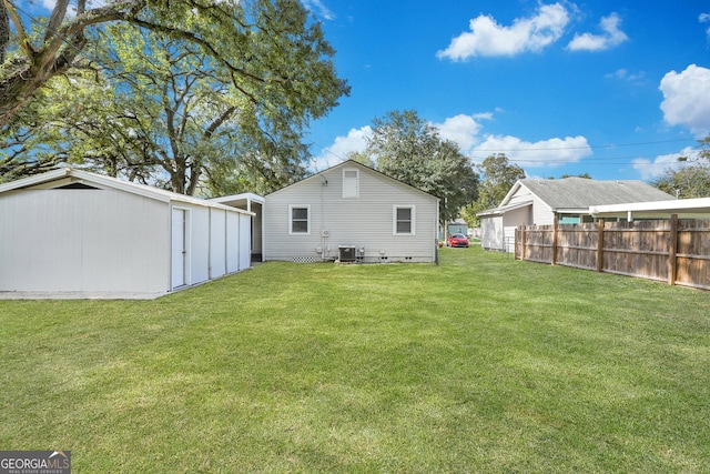 rear view of property featuring central AC unit and a lawn