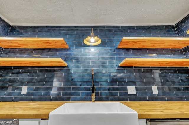 kitchen with sink, a textured ceiling, and wood counters