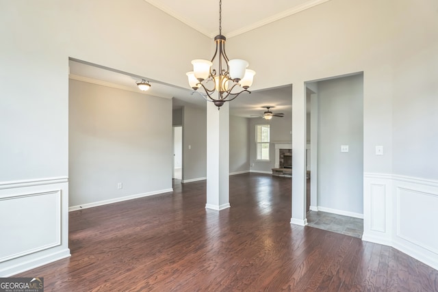 empty room featuring dark wood-type flooring, ceiling fan with notable chandelier, and crown molding