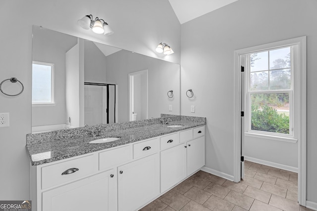 bathroom featuring vanity, vaulted ceiling, a healthy amount of sunlight, and a shower with shower door