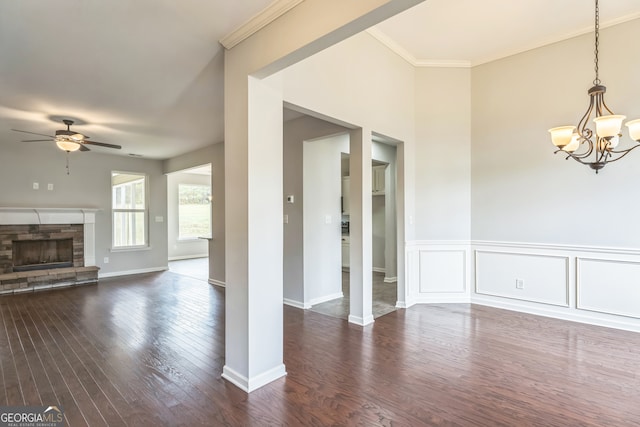 unfurnished living room with a fireplace, ceiling fan with notable chandelier, dark hardwood / wood-style floors, and crown molding