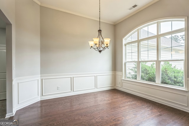 empty room featuring ornamental molding, dark hardwood / wood-style floors, a healthy amount of sunlight, and a notable chandelier