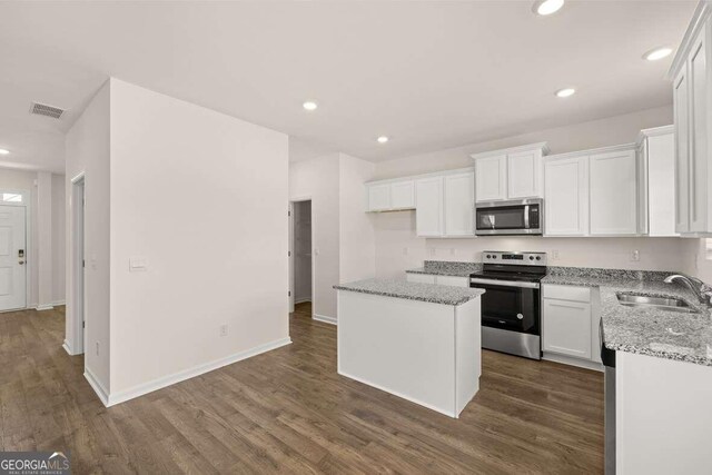 kitchen with stainless steel appliances, a kitchen island, white cabinetry, and sink