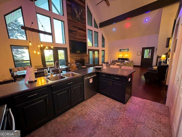 kitchen featuring high vaulted ceiling, stainless steel dishwasher, sink, and a fireplace