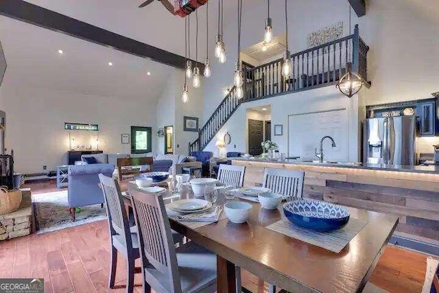 dining area featuring high vaulted ceiling, sink, hardwood / wood-style flooring, and beam ceiling