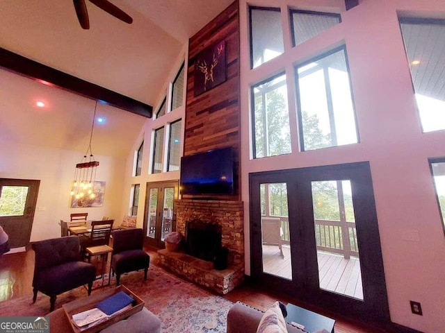 living room featuring a fireplace, high vaulted ceiling, hardwood / wood-style floors, beamed ceiling, and ceiling fan with notable chandelier