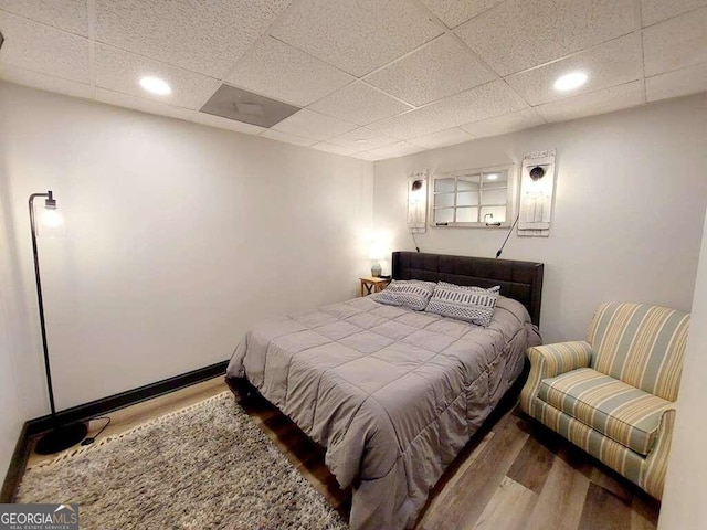 bedroom with hardwood / wood-style flooring and a paneled ceiling