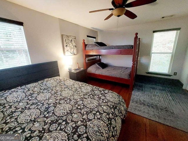 bedroom featuring multiple windows, ceiling fan, and dark hardwood / wood-style floors