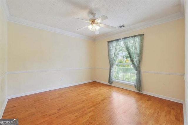 empty room with ceiling fan, wood-type flooring, a textured ceiling, and ornamental molding