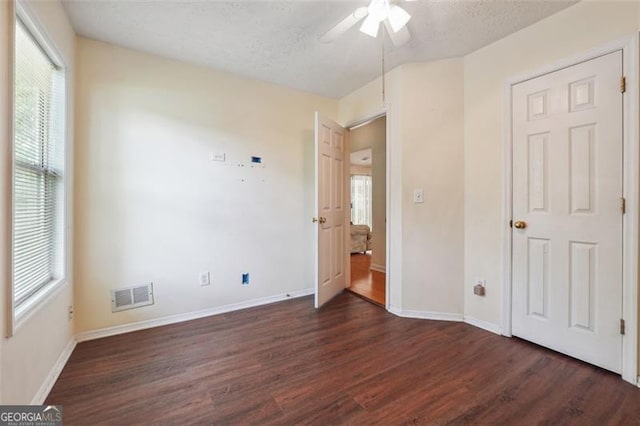 unfurnished bedroom featuring ceiling fan, dark hardwood / wood-style floors, and a textured ceiling