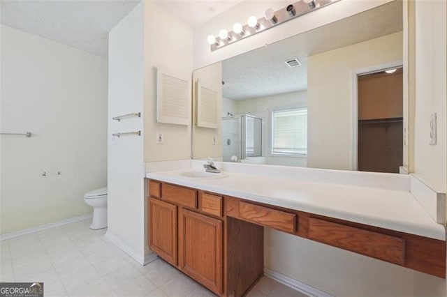 bathroom featuring vanity, toilet, an enclosed shower, and a textured ceiling