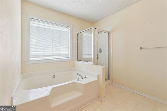 bathroom with a textured ceiling and shower with separate bathtub