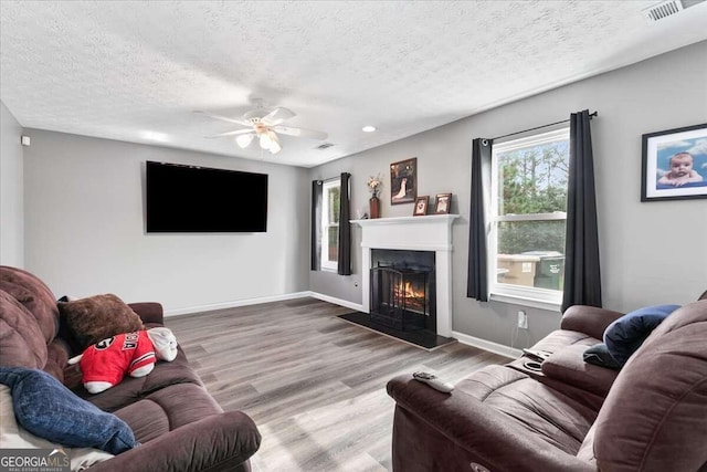 living room featuring hardwood / wood-style floors, ceiling fan, and a textured ceiling